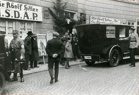 Vor dem Hotel Lord in Weilburg steht ein Sanitätswagen, um den sich einige Männer in NSDAP-Uniformen versammelt haben, 1933