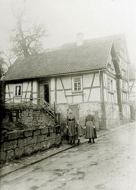Zwei Frauen mit einem Mädchen vor dem Haus in der Fahrgasse in Bersrod, 1910