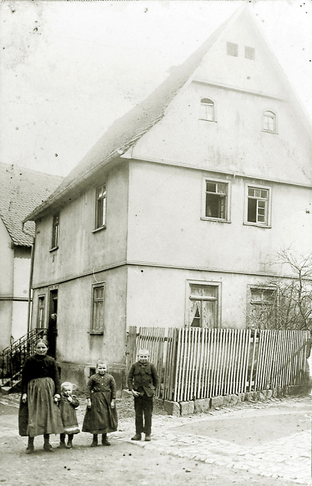 Frau mit drei Kindern vor ihrem Haus in der Brunnengasse in Hattenrod, 1910