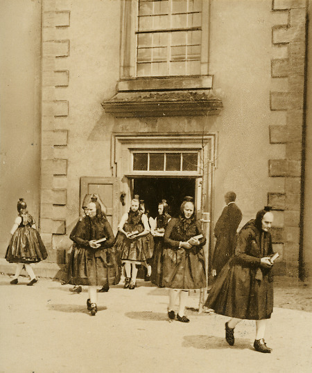 Frauen in Schwälmer Tracht verlassen die Kirche von Röllshausen, um 1938