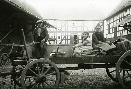 Zwei junge Frauen und ein junger Mann auf einem Fuhrwerk auf einem Hof in Rauschenberg, um 1940