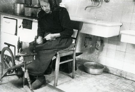 Ältere Frau aus Kerspenhausen (?) am Spinnrad in ihrer Küche, um, undatiert