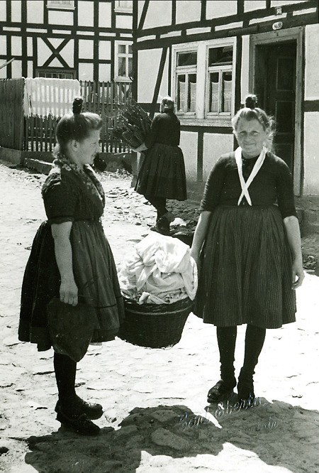 Zwei Frauen in Schwälmer Tracht mit einem Korb voll Wäsche, um 1938