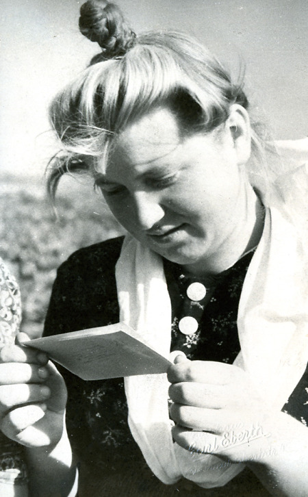 Junge Frau in Schwälmer Tracht beim Lesen eines Briefes, um 1940