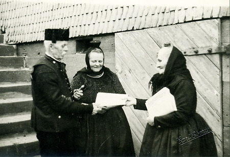 Die Briefträgerin in Wiera bei einem älteren Ehepaar, um 1950