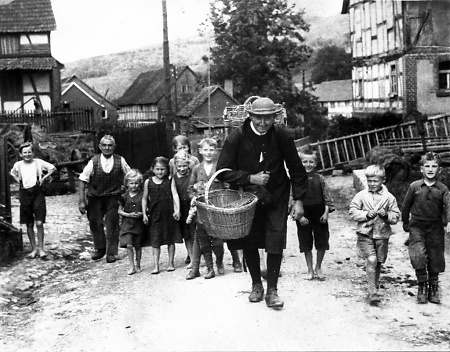 Ein Schwälmer Korbhausierer wird umschwärmt von Dorfkindern, 1920er Jahre?