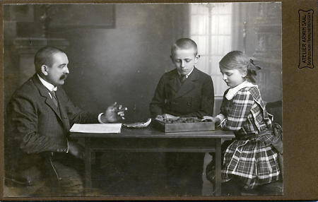 Vater mit Tochter und Sohn beim Spiel, um 1900