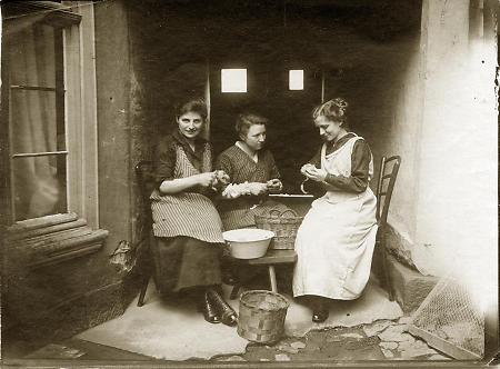 Drei junge Frauen beim Kartoffelschälen, um 1900