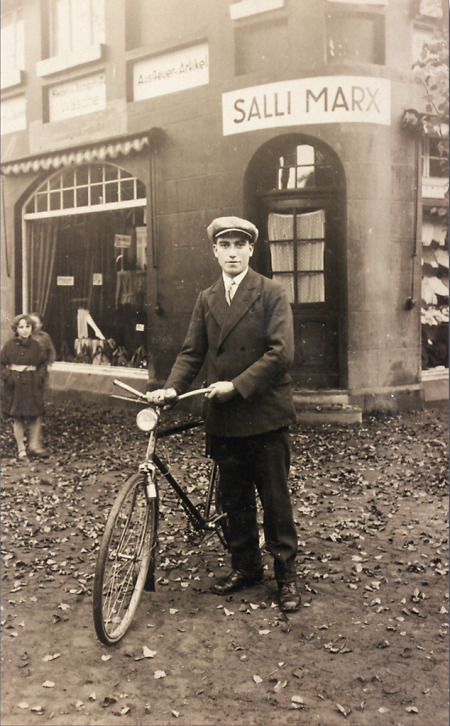 Junger Mann mit Fahrrad vor einem Aussteuer- und Wäschegeschäft in Frankenberg (?), um 1918