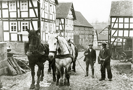 Zwei Männer mit einem Vierer-Pferdegespann auf der Dorfstraße in Hachborn, um 1930