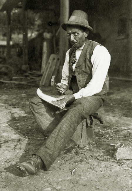 Älterer Mann in Weschnitz beim Dengeln einer Sense, 1907
