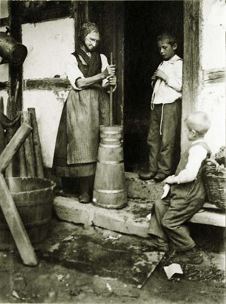 Frau mit Kindern beim Herstellen von Butter in Ober-Ostern, 1907/1908