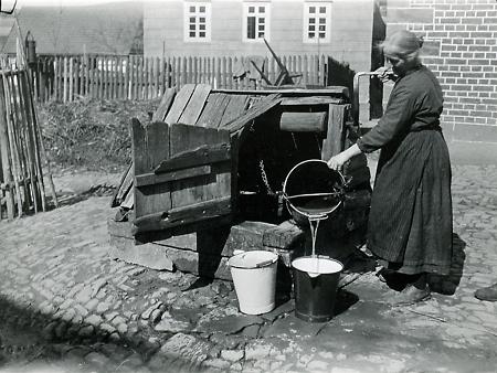 Frau am Brunnen in Willersdorf, um 1890